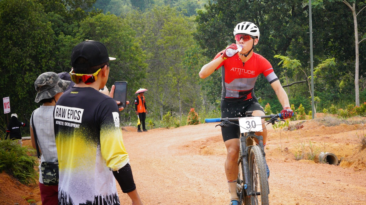 Cyclist taking on water at a feed station during a race — fuelling is a trainable skill, not an afterthought