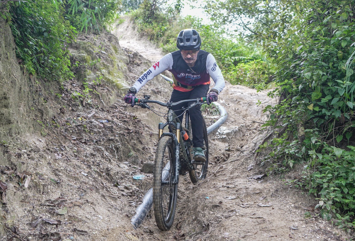 MTB rider on a technical muddy descent wearing a full trail helmet with MIPS protection